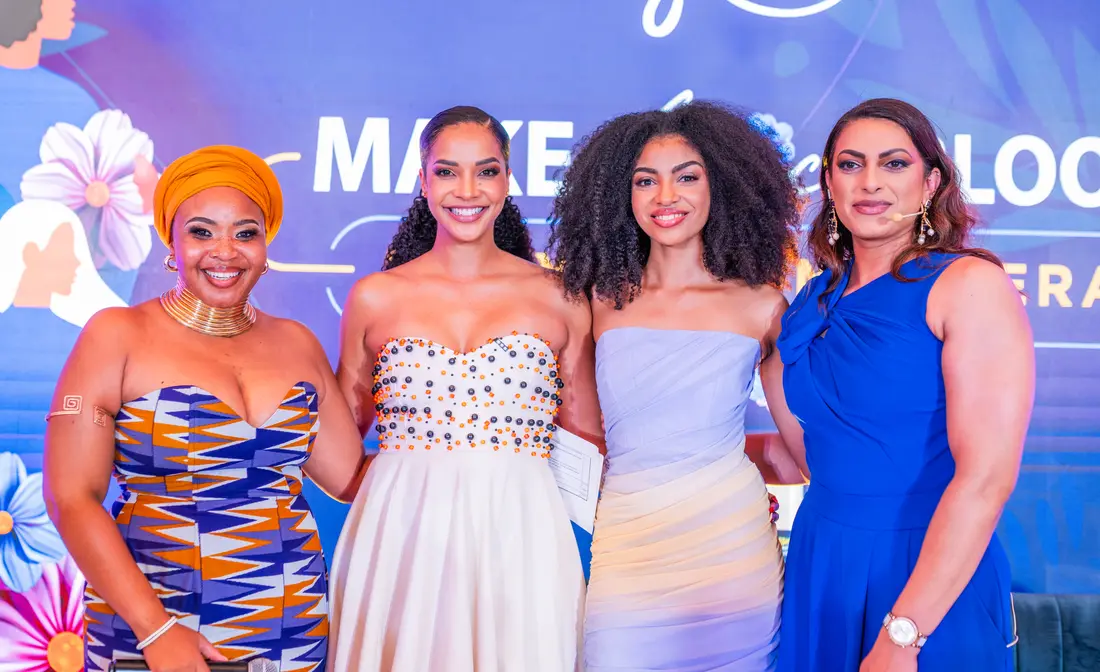 Four women in eveningwear in front of a Make Africa Bloom backdrop